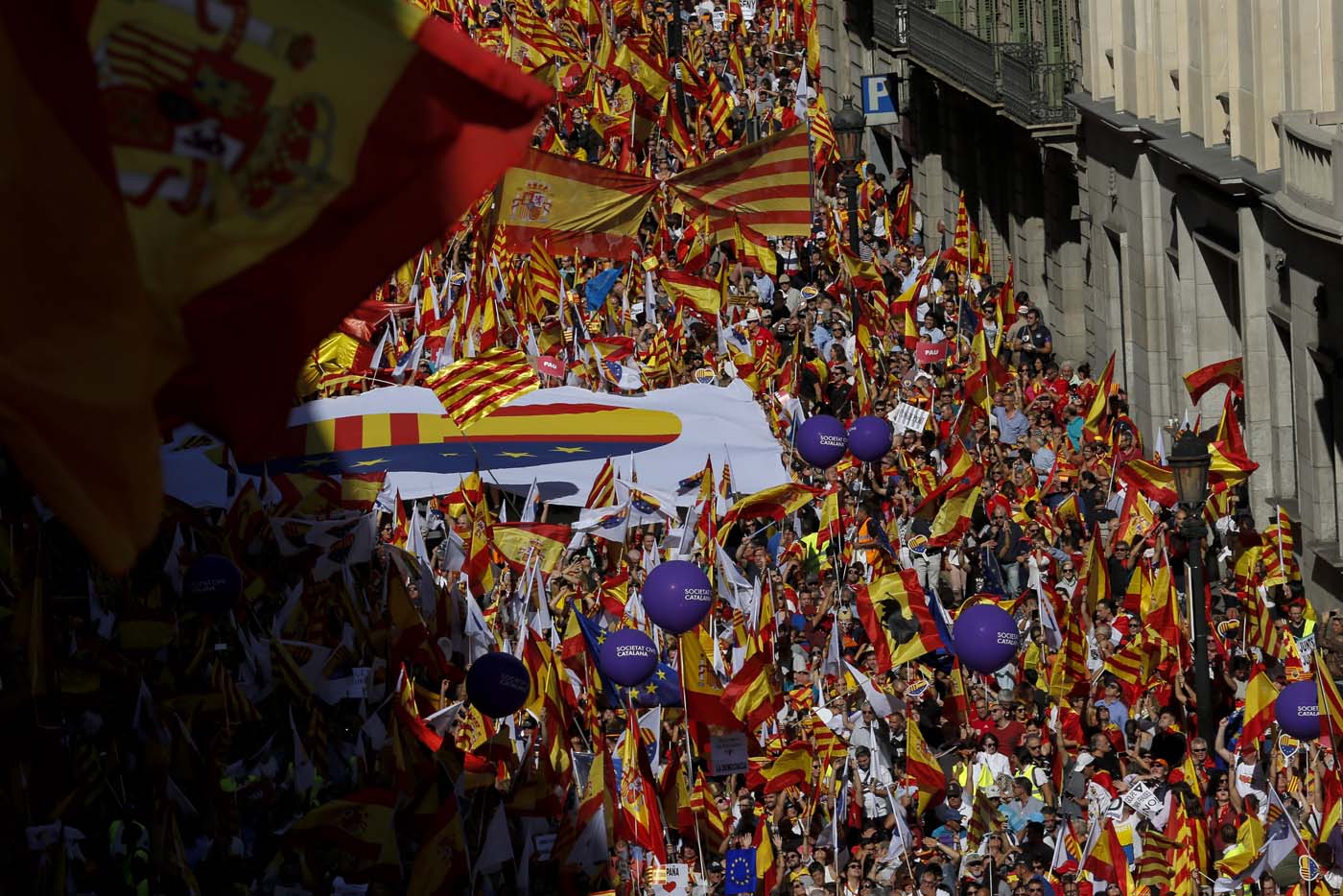Protesters hold Spanish flags during a demonstration called by "Societat Civil Catalana" (Catalan Civil Society) to support the unity of Spain on October 8, 2017 in Barcelona. Spain braced for more protests despite tentative signs that the sides may be seeking to defuse the crisis after Madrid offered a first apology to Catalans injured by police during their outlawed independence vote. / AFP PHOTO / PAU BARRENA
