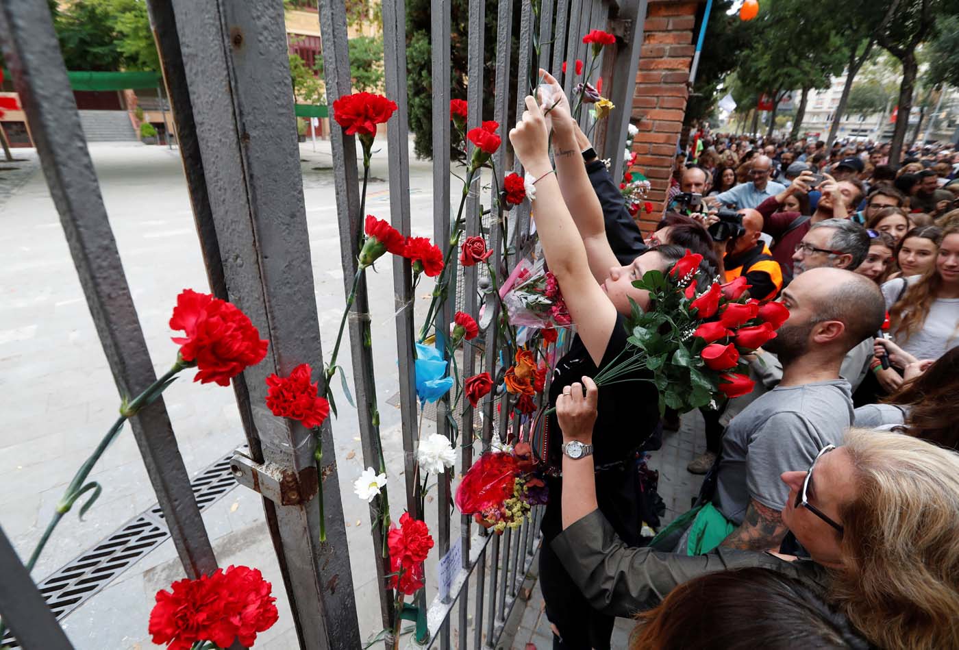 People place flowers on the gate of the Ramon Llull high school where Spanish police clashed with voters in the banned referendum in Barcelona, Spain October 3, 2017. REUTERS/Yves Herman