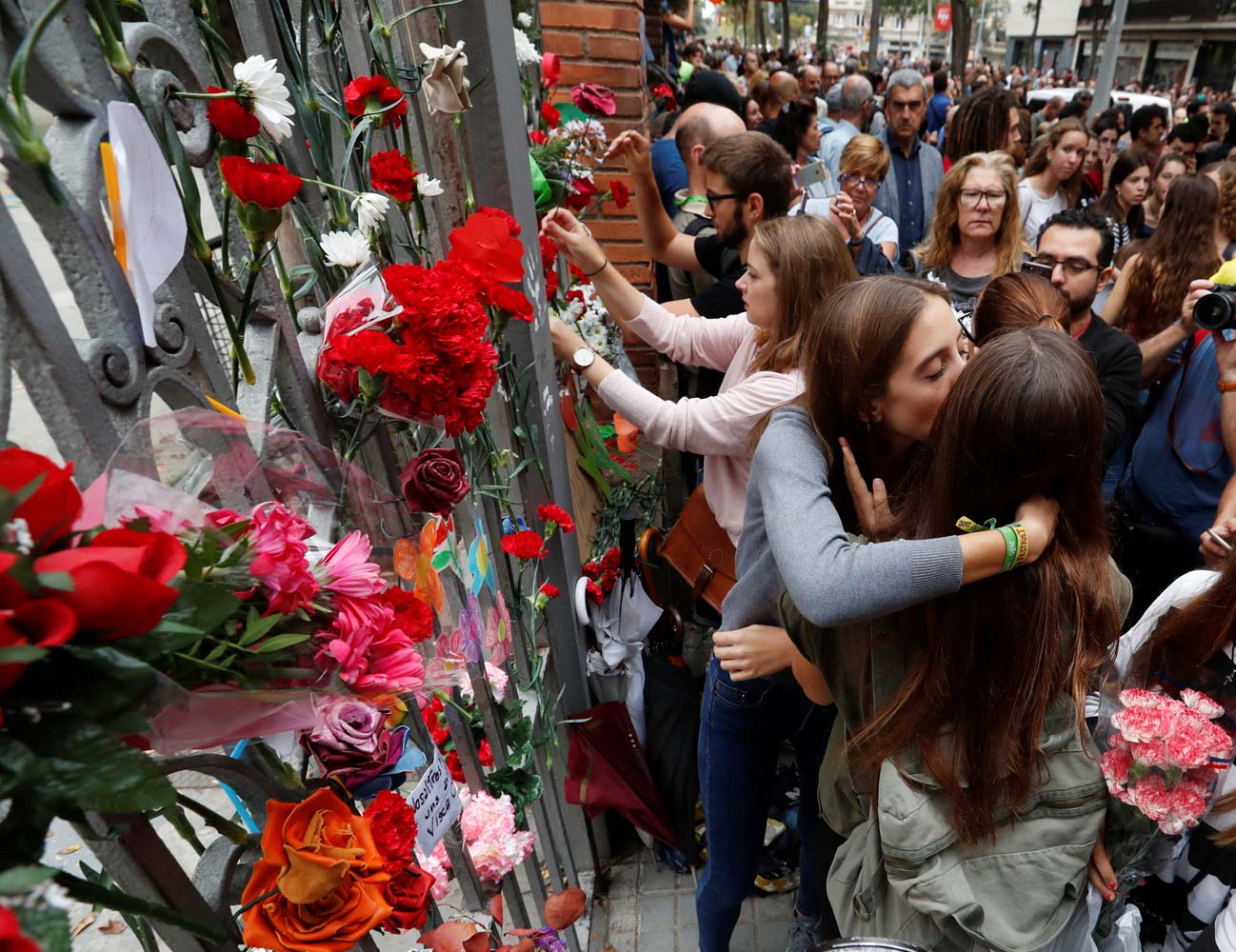 People place flowers on the gate of the Ramon Llull high school where Spanish police clashed with voters during the banned referendum in Barcelona, Spain October 3, 2017. REUTERS/Yves Herman