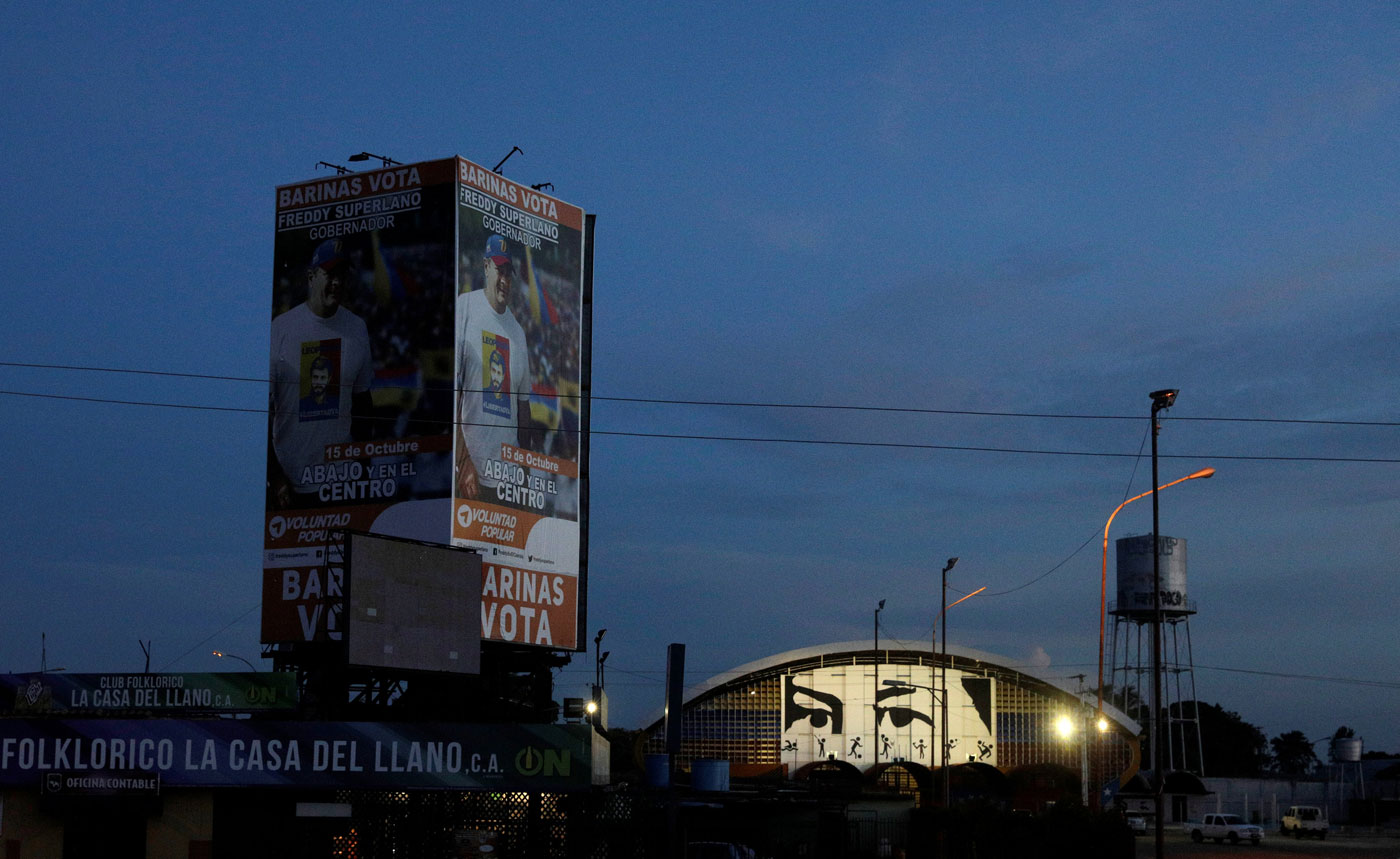 Democratic Unity coalition candidate for Barinas state Freddy Superlano is pictured on a building, near a painting depicting the eyes of Venezuela's late President Hugo Chavez, in Barinas, Venezuela