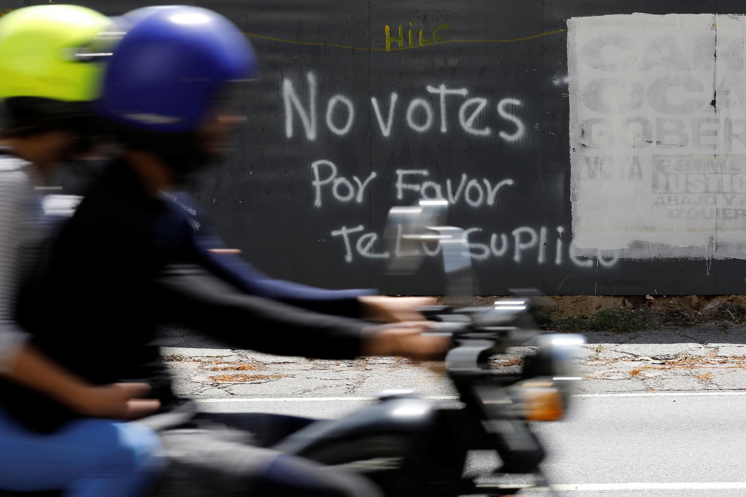 Una motocicleta atraviesa delante de un graffiti pintado en una barda en Caracas, Venezuela, 12 de mayo, 2018. El grafiti dice: "No votes, por favor te lo suplico". REUTERS/Carlos Jasso - RC1B4B72EEA0
