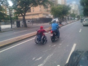 En su silla de ruedas, agarrado de una moto y por el medio de la calle (foto)