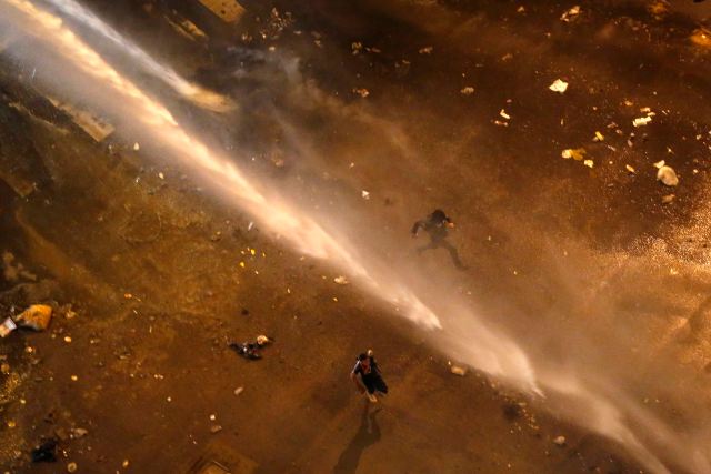 Anti-government protesters run away from a water cannon shot by the national guard during a protest at Altamira square in Caracas
