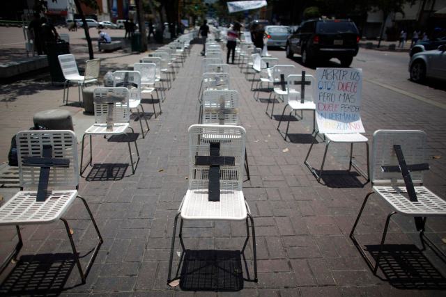 Anti-government protesters placed black crosses on white chairs, representing victims who died from violence, during a demonstration in Caracas