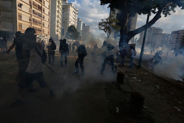 Anti-government protesters run from tear gas during a protest against Nicolas Maduro's government at Altamira square in Caracas