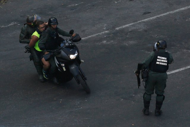 Members of the National Guard detain an anti-government protester during a protest against Nicolas Maduro's government at Altamira square in Caracas
