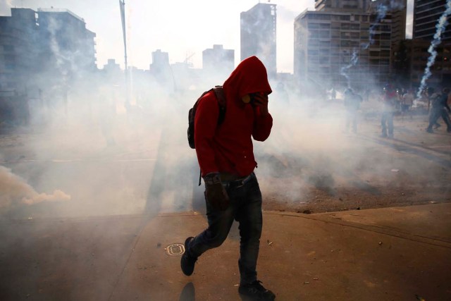 An anti-government protester walks amidst teargas during clashes with police at Altamira square in Caracas