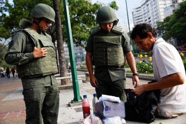 National guards conduct a spot-check on a man at Altamira square in Caracas