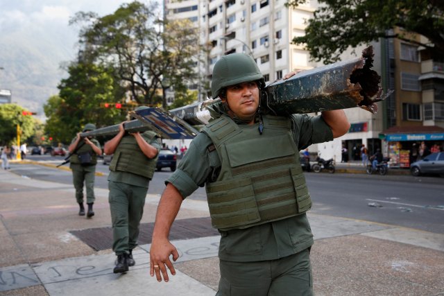 National Guards carry a damaged utility pole that was used as a barricade by protesters at Altamira square in Caracas