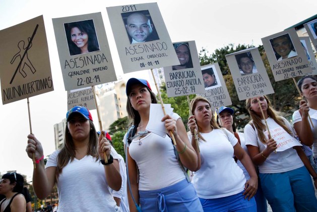 Opposition students hold photographs of victims of violence during a protest in Caracas