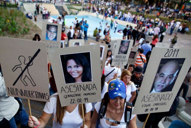 Opposition students hold photographs of victims of violence during a protest in Caracas