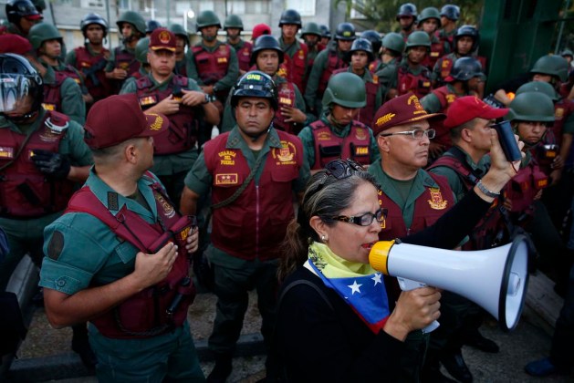 An opposition supporter speaks in front of National Guards during a protest in Caracas
