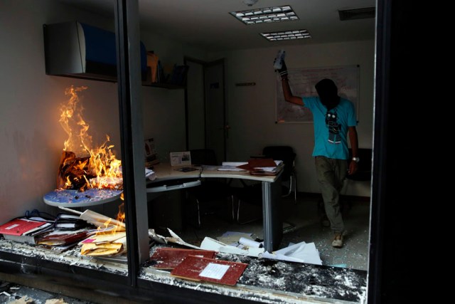An anti-government protester sets fire to an office as they loot a public building in Caracas