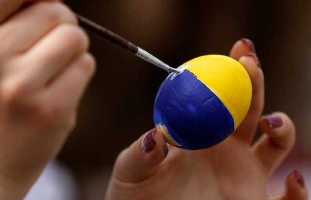 A woman paints an artificial egg on the eve of Easter ahead of midnight Easter mass in Luhansk