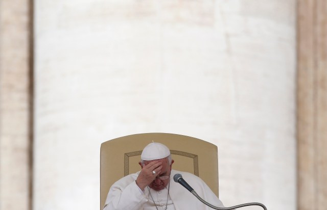 Pope Francis touches his forehead as he leads the general audience in Saint Peter's square at the Vatican