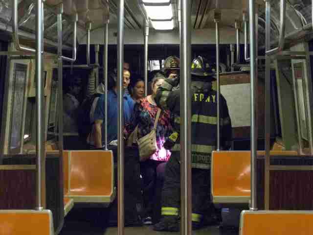 Firefighters instruct passengers on how to exit a subway car after it derailed in the Woodside neighborhood in the Queens borough of New York