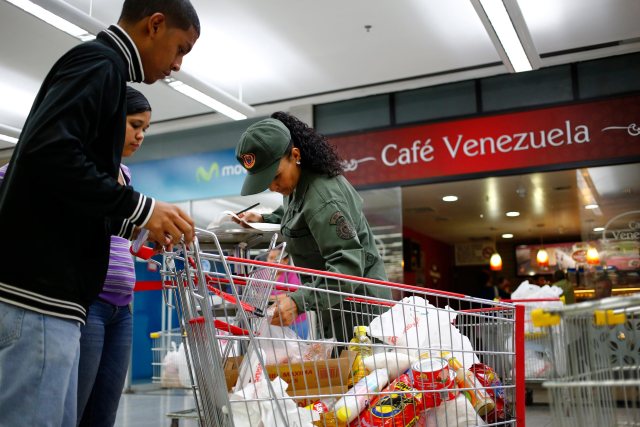 Un reservista del ejército comprueba una lista de elementos comprar de la gente se va con sus compras en un supermercado Bicentenario estatal en Caracas 02 de mayo 2014. 