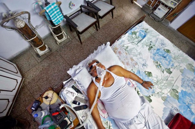 L.D. Chopra, de 76 años, un paciente asmático, respira a través de una máscara de oxígeno mientras está acostado en una cama en su residencia en Nueva Delhi (Anindito Mukherjee/ Reuters)