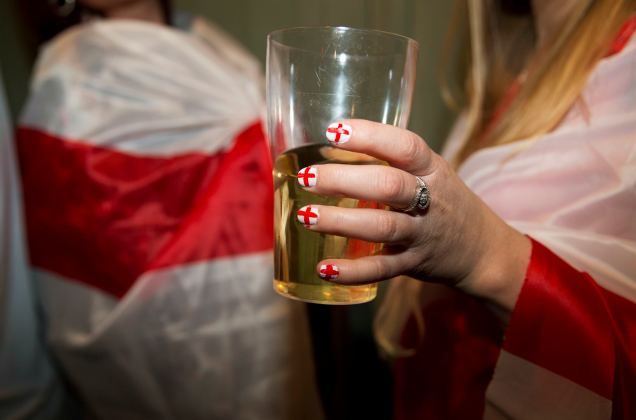 A England soccer fan holds a glass with her nails painted in her teams colours as she watches her team play against Italy during the 2014 World Cup at a bar in central London
