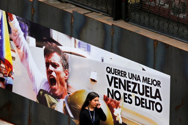 A woman walks past a banner with a picture of jailed opposition leader Leopoldo Lopez in Caracas
