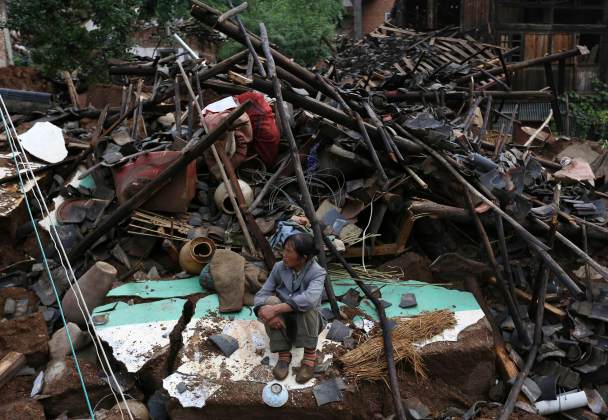A woman sits among debris after an earthquake hit Longtoushan township of Ludian county