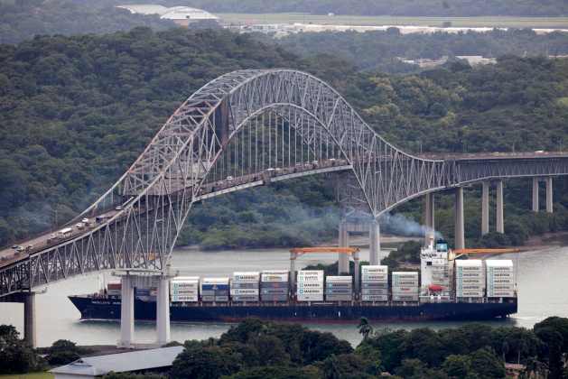 A container ship sails underneath the Bridge of the Americas in the Panama Canal in Panama City