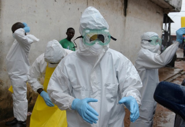 Health workers wearing protective clothing prepare to carry an abandoned dead body presenting with Ebola symptoms at Duwala market in Monrovia