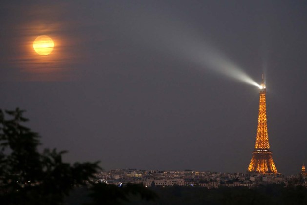 A super moon rises in the sky near the Eiffel tower as seen from the suburb town of Suresnes