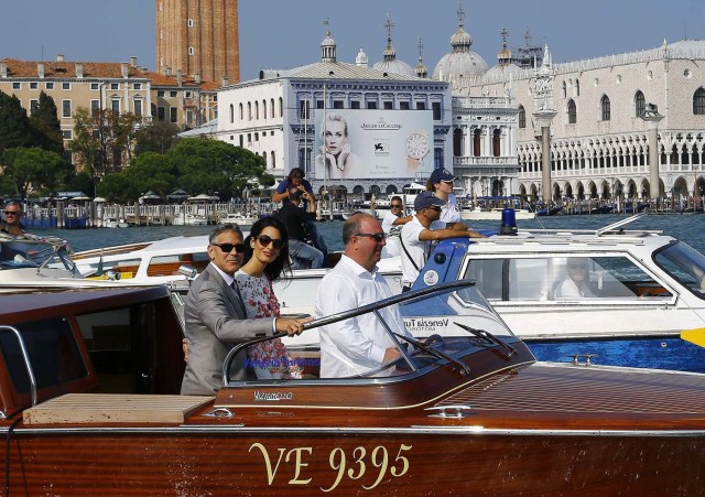 U.S. actor George Clooney and his wife Amal Alamuddin stand on a water taxi on the Grand Canal in Venice