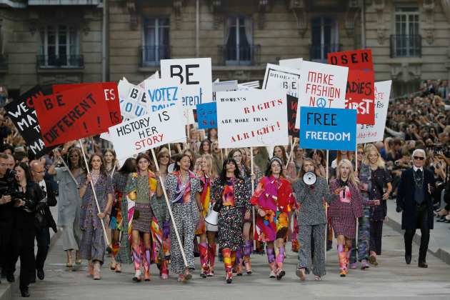 German designer Karl Lagerfeld appears with models who stage a demonstration at the end of his Spring/Summer 2015 women's ready-to-wear collection for French fashion house Chanel in Paris