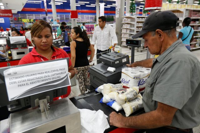 A customer puts his finger on a fingerprint scanner as part of the process to buy goods at Bicentenario in Caracas