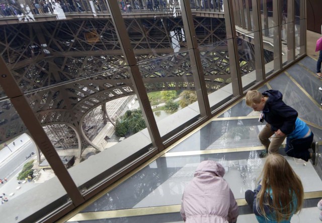 Visitors stand on the new glass floor at the Eiffel Tower in Paris
