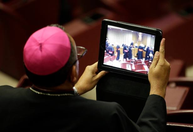 A bishop takes a picture with a tablet during a synod of bishops in Paul VI's hall at the Vatican