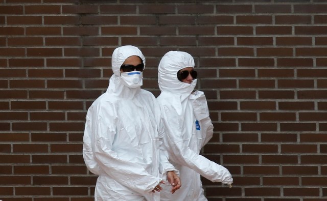 Trabajadores en trajes protectores en la entrada del apartamento de una enfermera con ébola en Alcorcón, cerca de Madrid