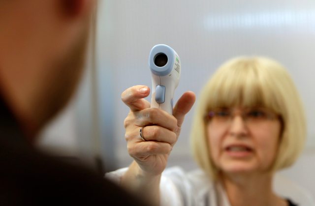 Una doctora del aeropuerto de Praga muestra el uso de un termómetro (Foto Reuters)