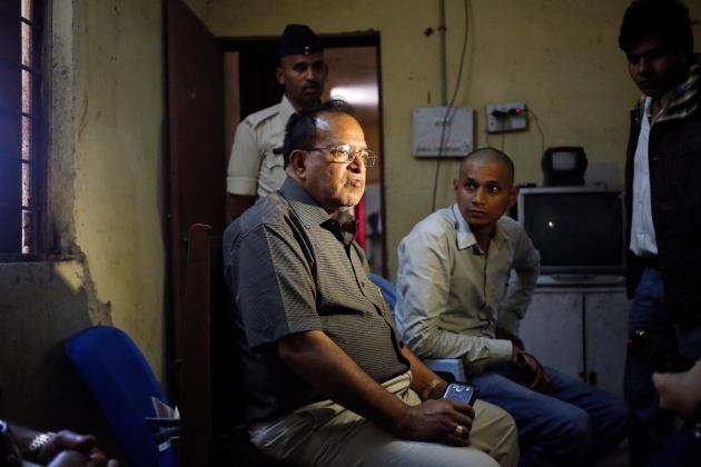 R.K.Gupta, a doctor who performed sterlisation surgeries at a government mass sterilisation "camp", sits at a police station as police and the media look on in Bilaspur