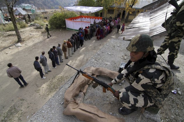 Un soldado vigila mientras varios votantes guardan su turno ante un colegio electoral para participar en la jornada inaugural de las elecciones de la Cachemira india en Bhadarwah, a unos 210 kilómetros de Jammu, la capital de invierno de Cachemira. Muchos votantes desafiaron el frío e hicieron cola antes de la apertura de 1.900 colegios para elegir a 15 de los 87 diputados de la Asamblea regional en un proceso de un mes de duración. EFE/Jaipal Singh