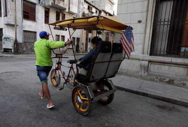 Un hombre empuja su taxi triciclo con una bandera de Estados Unidos en una calle en La Habana (Foto Reuters)