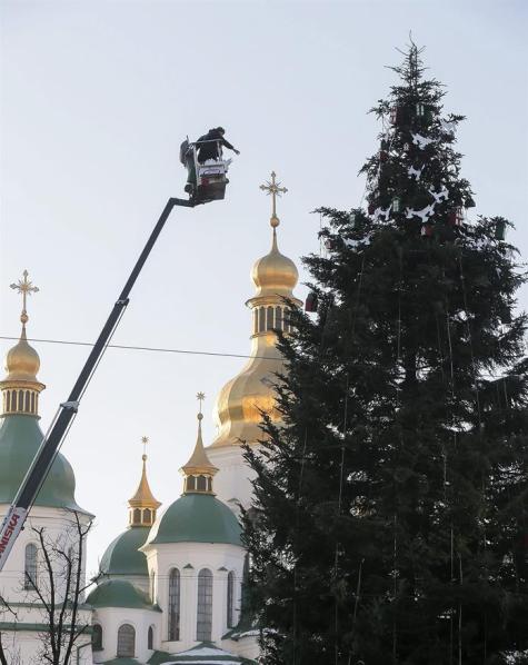 Unos trabajadores adornan un árbol de Navidad frente a la catedral de Santa Sofía en Kiev, Ucrania, hoy, lunes 15 de diciembre de 2014. El presidente de Ucrania, Petró Poroshenko, cifró ayer en más de 600 los soldados gubernamentales en manos de los rebeldes y de la vecina Rusia, y pidió su liberación antes de finales de año. "El objetivo es que para Navidad todos los que están en las listas, y son más de 600, deben haber regresado a sus casas", dijo Poroshenko durante una reunión del Consejo de Seguridad de Ucrania, según medios locales. EFE/Sergey Dolzhenko