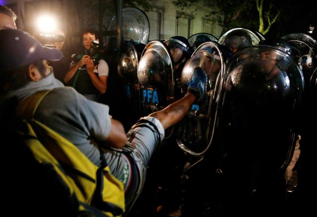 Demonstrator kicks a shield of an anti-riot policeman during a protest over the death of prosecutor Alberto Nisman, outside the Casa Rosada Presidential Palace in Buenos Aires