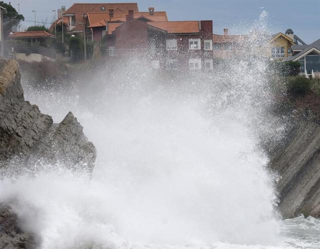 Una ola rompe junto a las casas de Liencres, en Cantabria, cuya comunidad se encuentra en alerta por fuertes vientos y fenomenos costeros. (foto EFE/ Pedro Puente Hoyos)