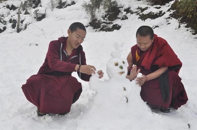 Dos monjes hacen un muñeco de nieve cerca de Dharamshala, en la India. (foto EFE/Sanjay Baid)