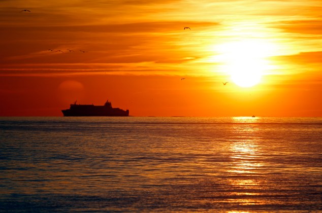 A passenger ferry sails during sunset off the coast of Marseille
