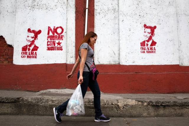 A woman walks past graffiti depicting U.S. President Barack Obama in Caracas