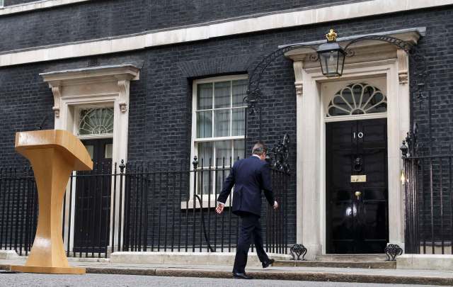 Britain's Prime Minister David Cameron walks back into 10 Downing Street after speaking upon his return after meeting with Queen Elizabeth at Buckingham Palace in central London