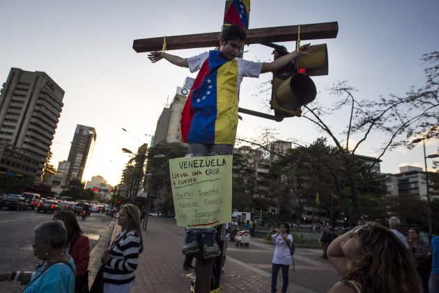 Un hombre se amarra simulando una crucifixión a modo de protesta contra el Gobierno venezolano, en el semáforo de una plaza hoy, miércoles 4 de marzo de 2015, en Caracas (Foto EFE)