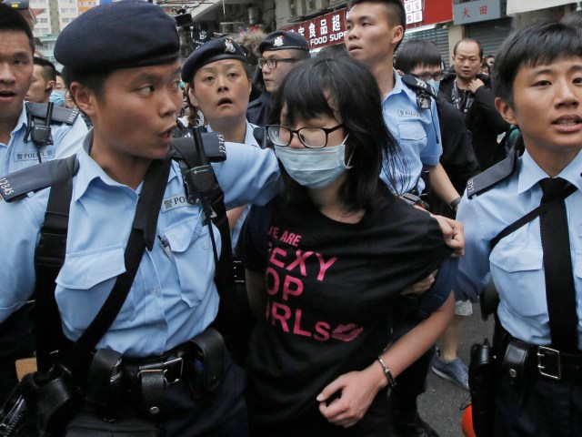 Agentes de policía custodian a una activista tras un enfrentamiento entre quienes protestaban contra la proliferación de compradores de la China continental y residentes de Yuen Long, en Hong Kong, el 1 de marzo de 2015. (Foto AP/Vincent Yu)