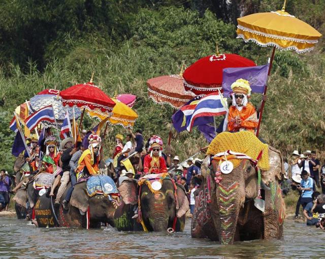 Novicios montados en elefantes se disponen a purificar sus cuerpos en las aguas del río Yom durante la ceremonia anual de ordenación en elefante, en la provincia de Sukhothai, al norte de Tailandia, hoy, martes 7 de abril de 2015. Según la religión budista en Tailandia, cada hombre es llamado a ser monje durante algún periodo de su vida para aprender las doctrinas budistas y ganarse el respeto para sus padres y sus familias. EFE/Pongmanat Tasiri