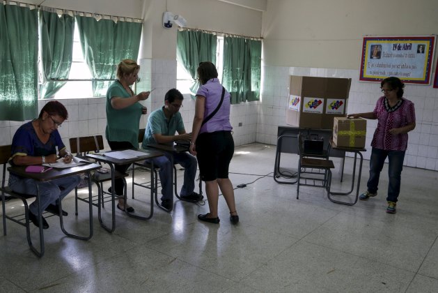 A woman casts her marked ballot in a box during opposition coalition primaries for parliamentary election Caracas