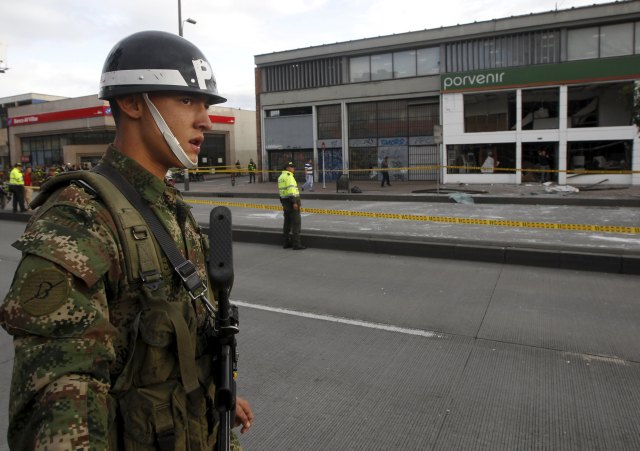 A soldier stands near policemen close to the site where an explosion occurred at the office of the Porvenir pension fund in downtown Bogota